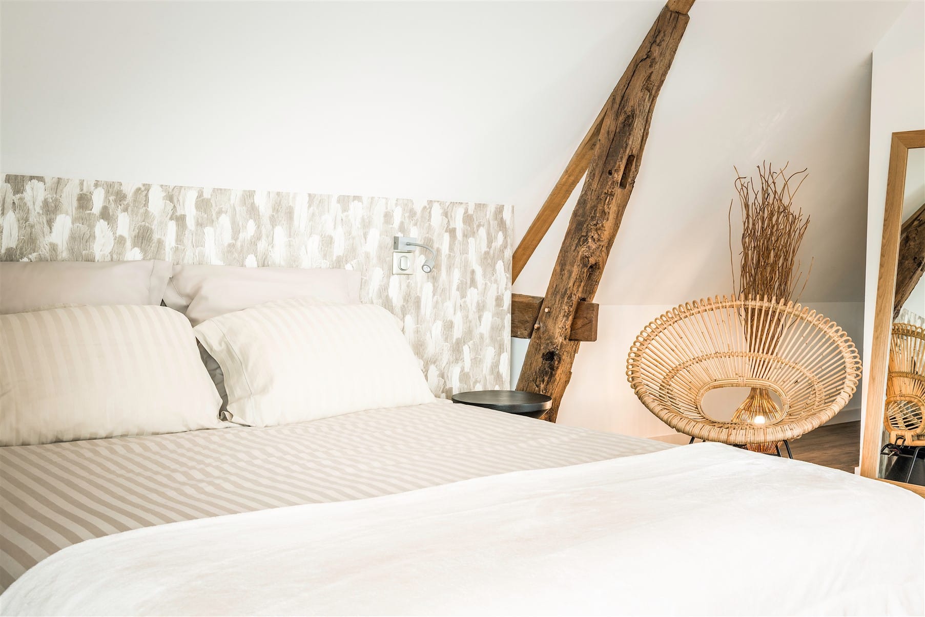 Vue lit double et tête de lit en papier-peint plumes, fauteuil en rotin, par Virginie Vaudenay, décoratrice UFDI, à Sancerre dans le Cher(18), la Nièvre(58), le Loiret(45), l'Yonne(89), et Sologne(41)