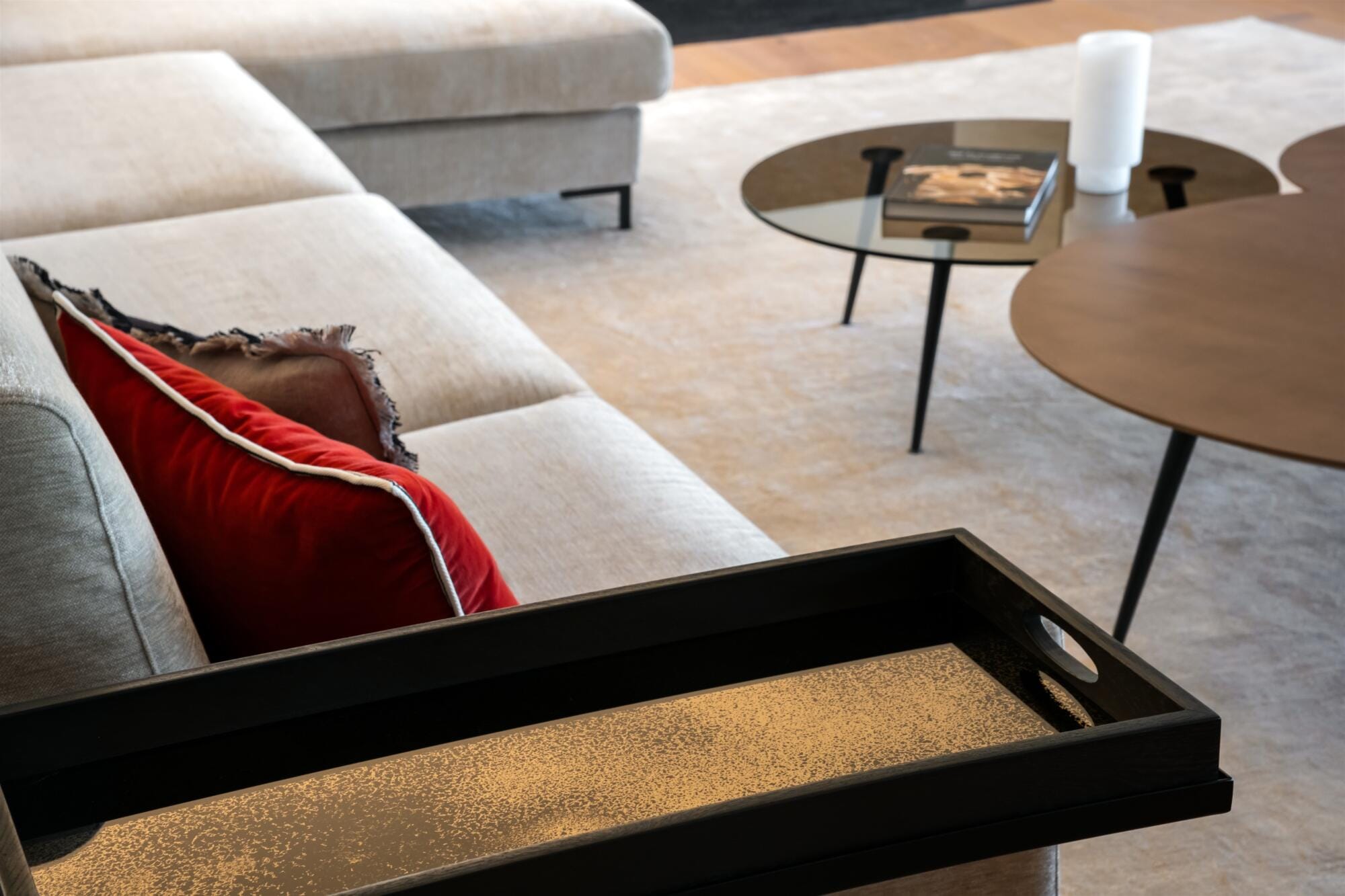 Gros plan bout de canapé et coussins velours rouge passepoilé, tables basses gigognes en verre fumé, par Virginie Vaudenay, Décoratrice UFDI à Sancerre, dans le Cher (18), la Nièvre (58) , le Loiret (45) et L’Yonne (89), Sologne(41)