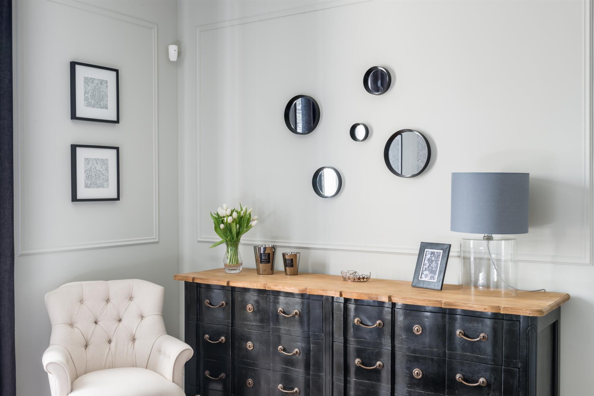 Gros plan commode ancienne noir et fauteuil capitonné beige, ensemble de miroirs ronds, par Virginie Vaudenay, décoratrice UFDI, à Sancerre dans le Cher(18), la Nièvre(58), le Loiret(45), l'Yonne(89), et Sologne(41)