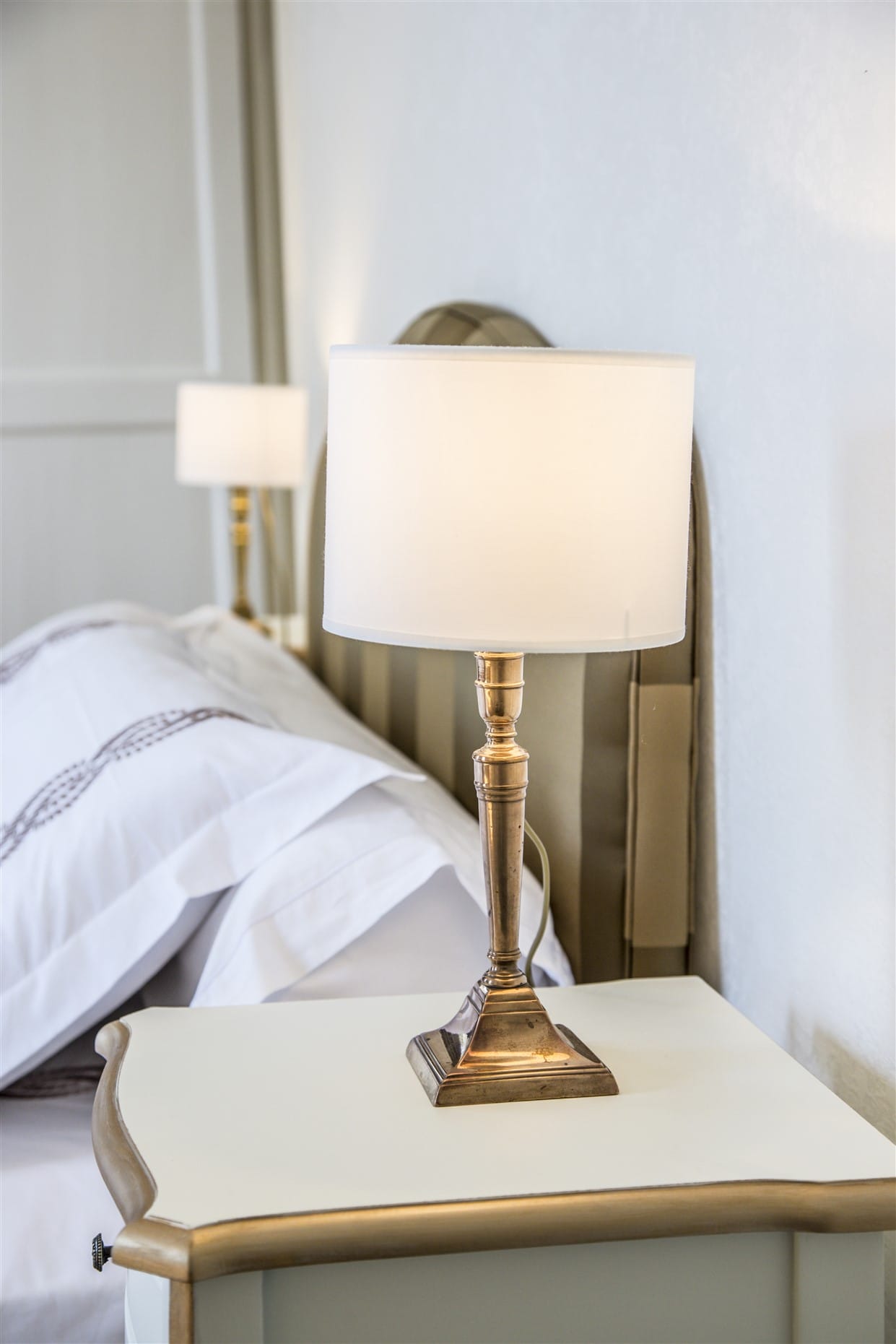 Gros plan chevet blanc or lampe laiton et tête de lit tapissée, par Virginie Vaudenay, décoratrice UFDI, à Sancerre dans le Cher(18), la Nièvre(58), le Loiret(45), l'Yonne(89), et Sologne(41)